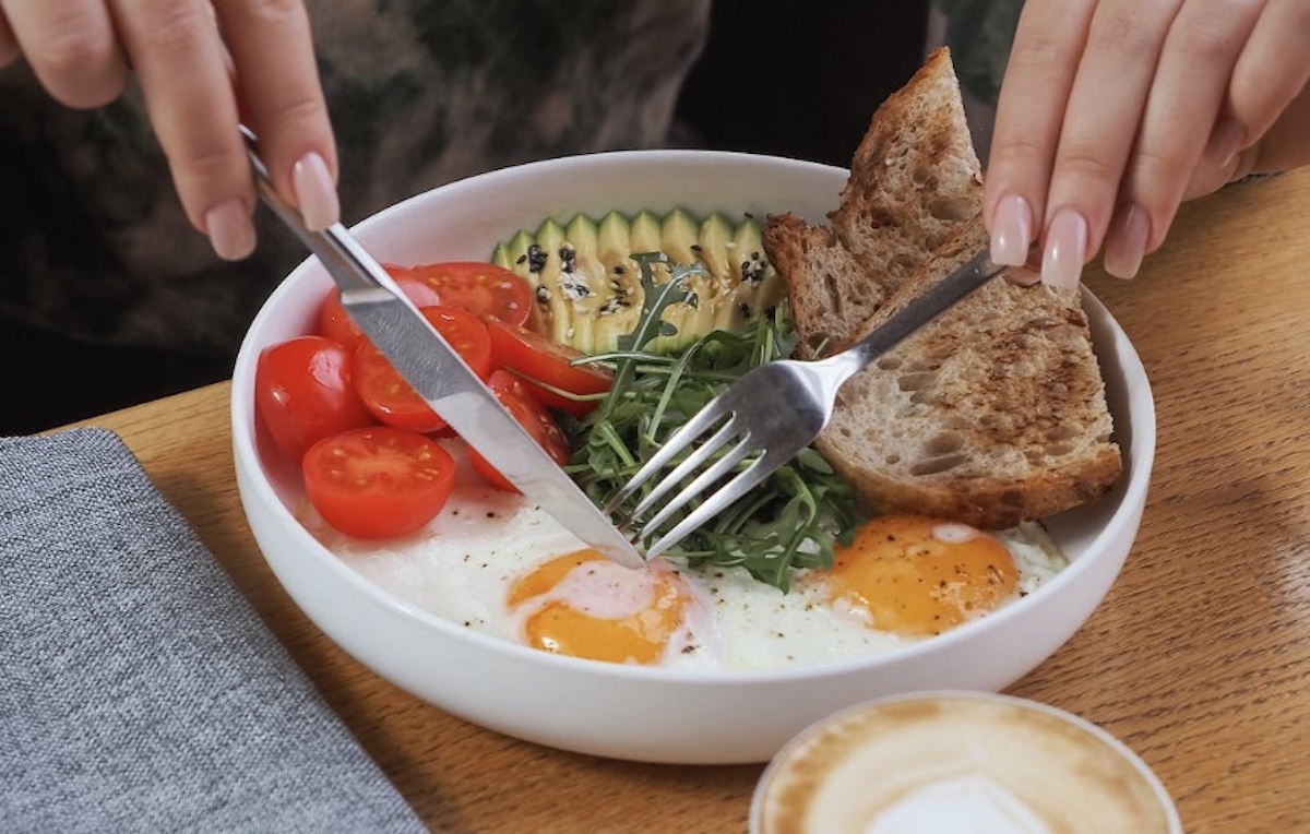 Eating breakfast plate with eggs toast and avocado