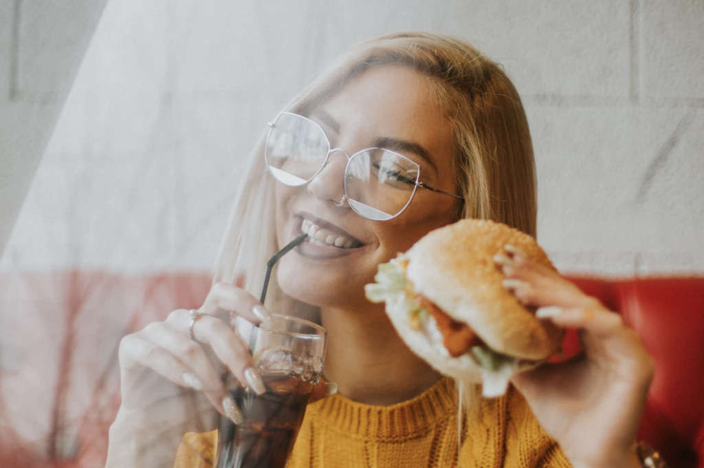Happy girl enjoying burger and a coke