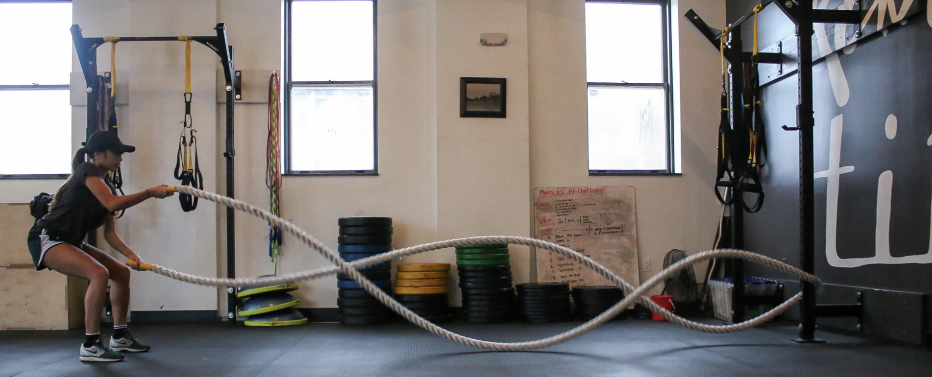 Woman is doing workout in a fitness room with rope