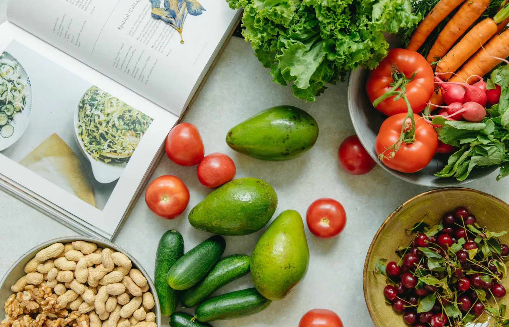 Vegetables and a cookbook on a table.