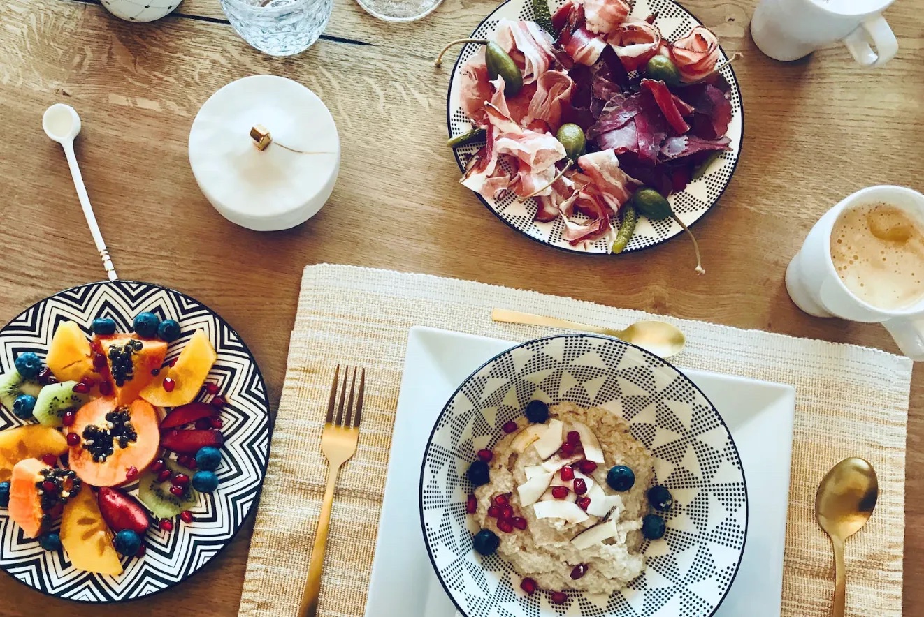 There are different foods on a table. Fruits and some meat.