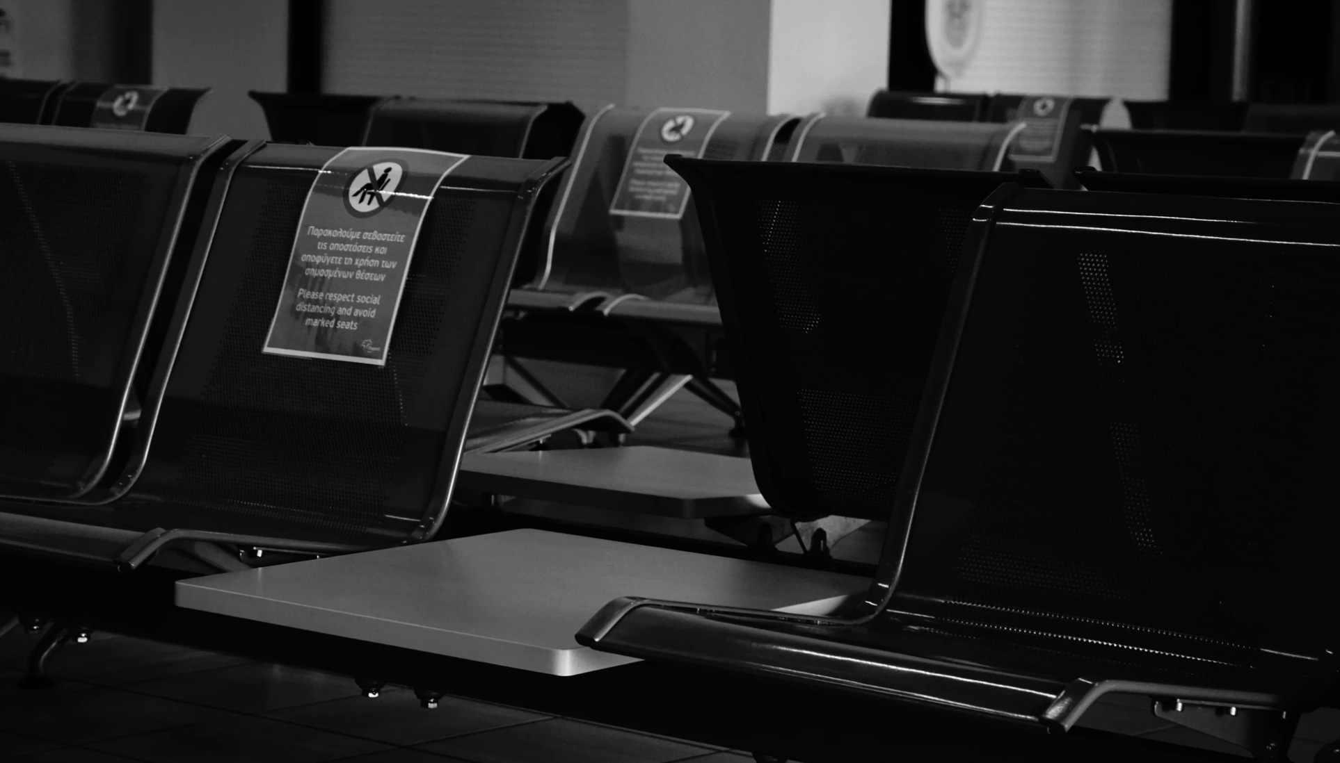 An empty airport with seats blocked off to practice social distancing. 