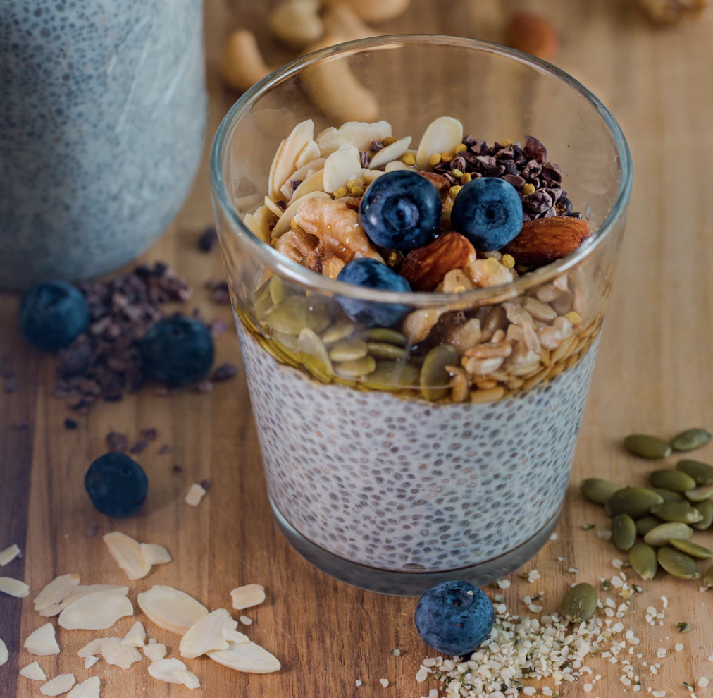 Chia seeds and other nuts and seeds in a cup with blueberries on top