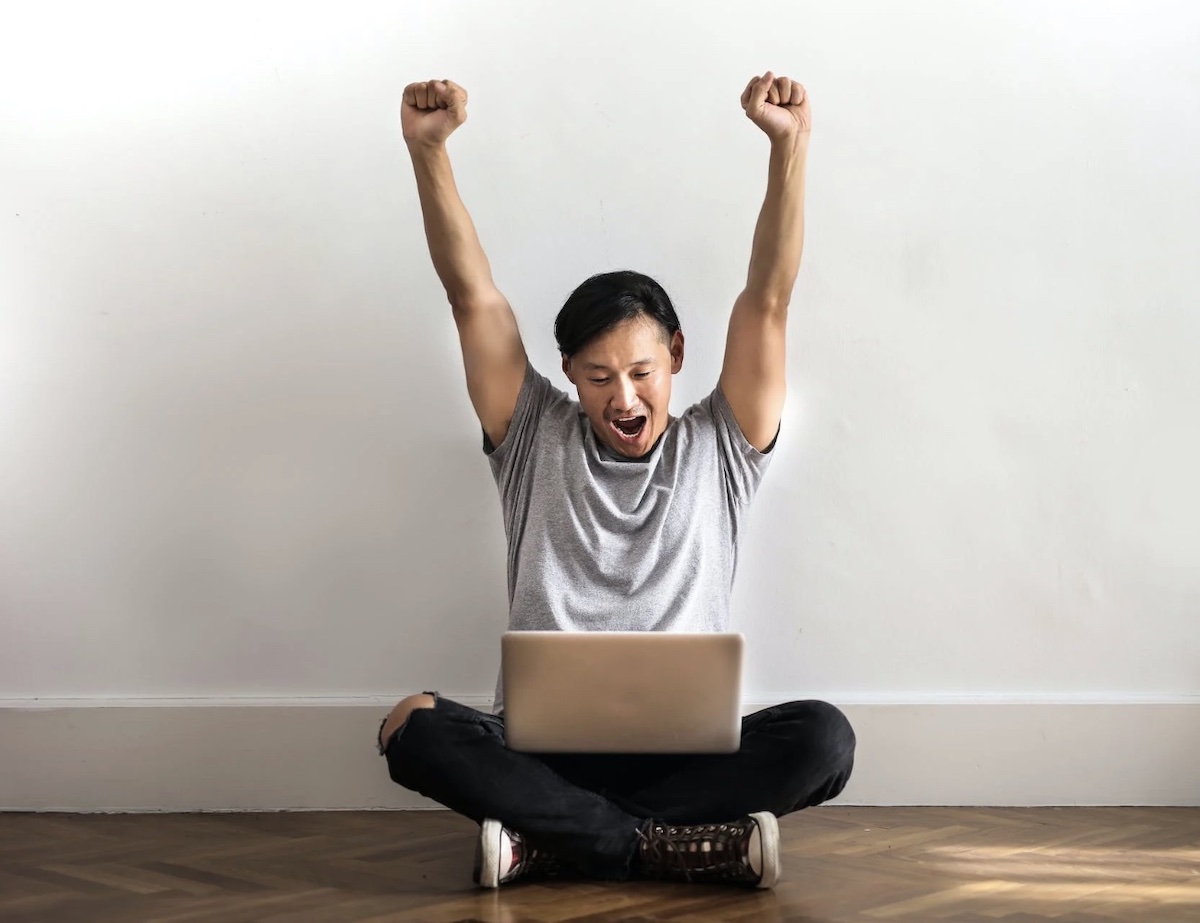 Man celebrating in front of computer on the ground