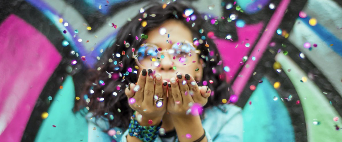 Girl blowing confetti to celebrate 