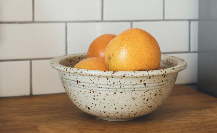 A bowl of oranges on a kitchen table