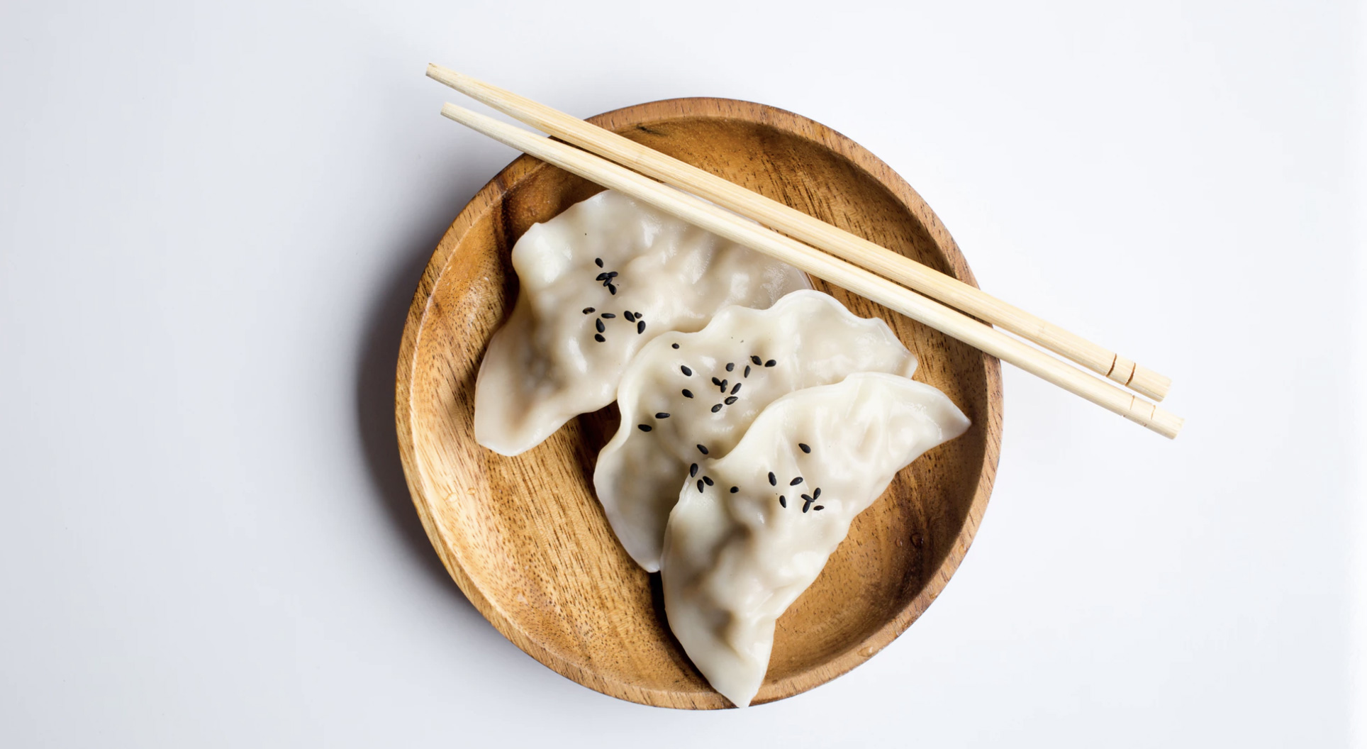 A wood plate with chopsticks on top of it with Chinese food 