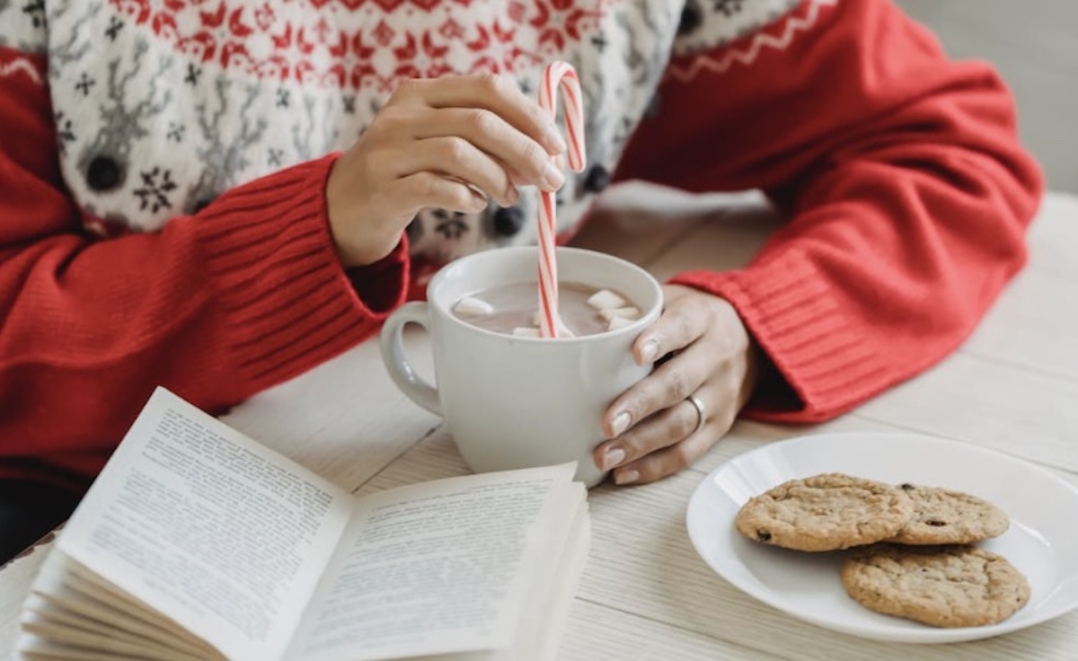 Woman mixing a hot chocolate and eating cookies during holidays