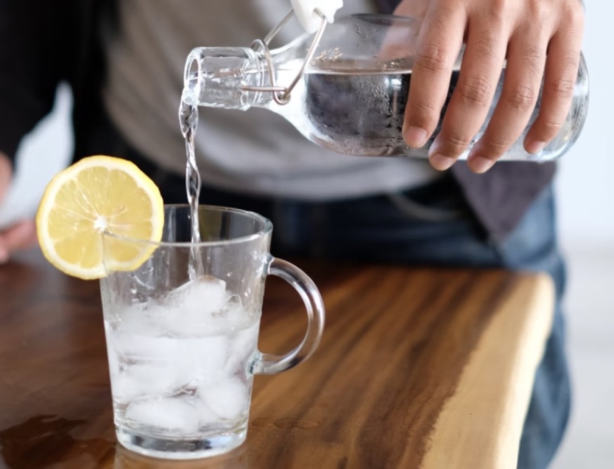 individual pouring water into a glass 