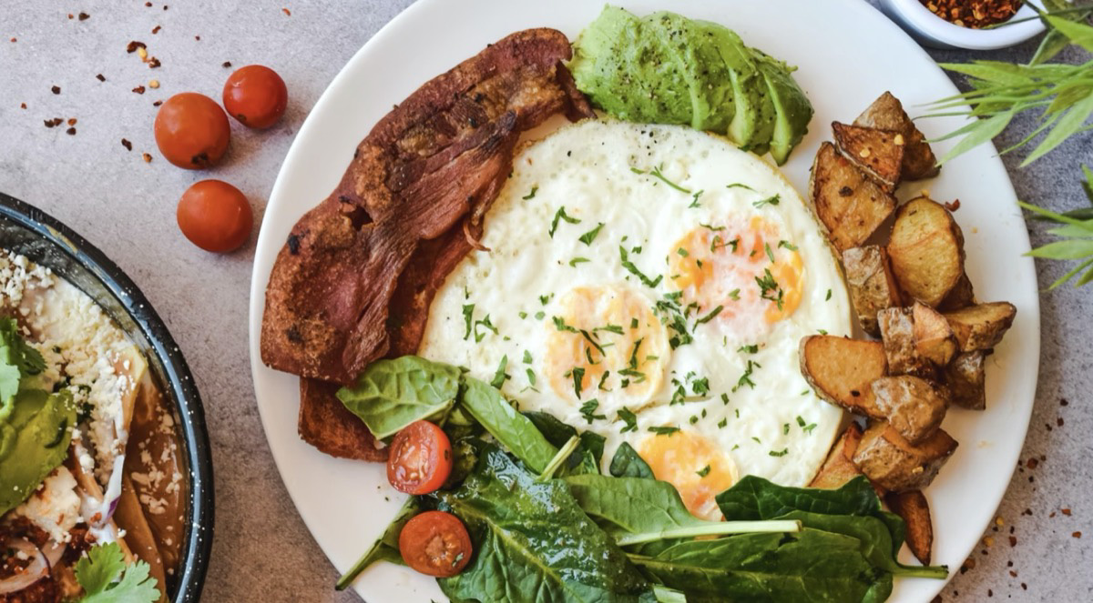 Eggs, potatoes, greens on a plate. 