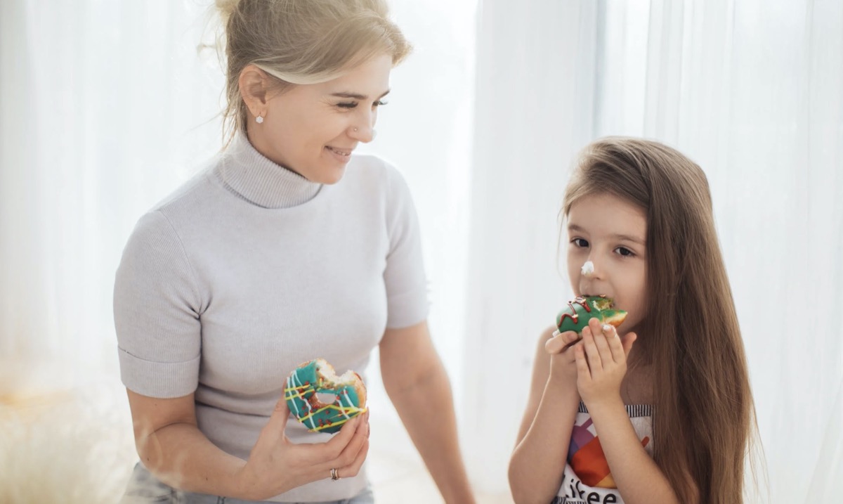 Mother and daughter eating donuts together