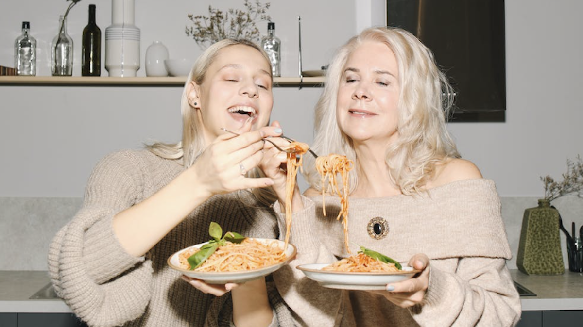 mother daughter eating pasta together