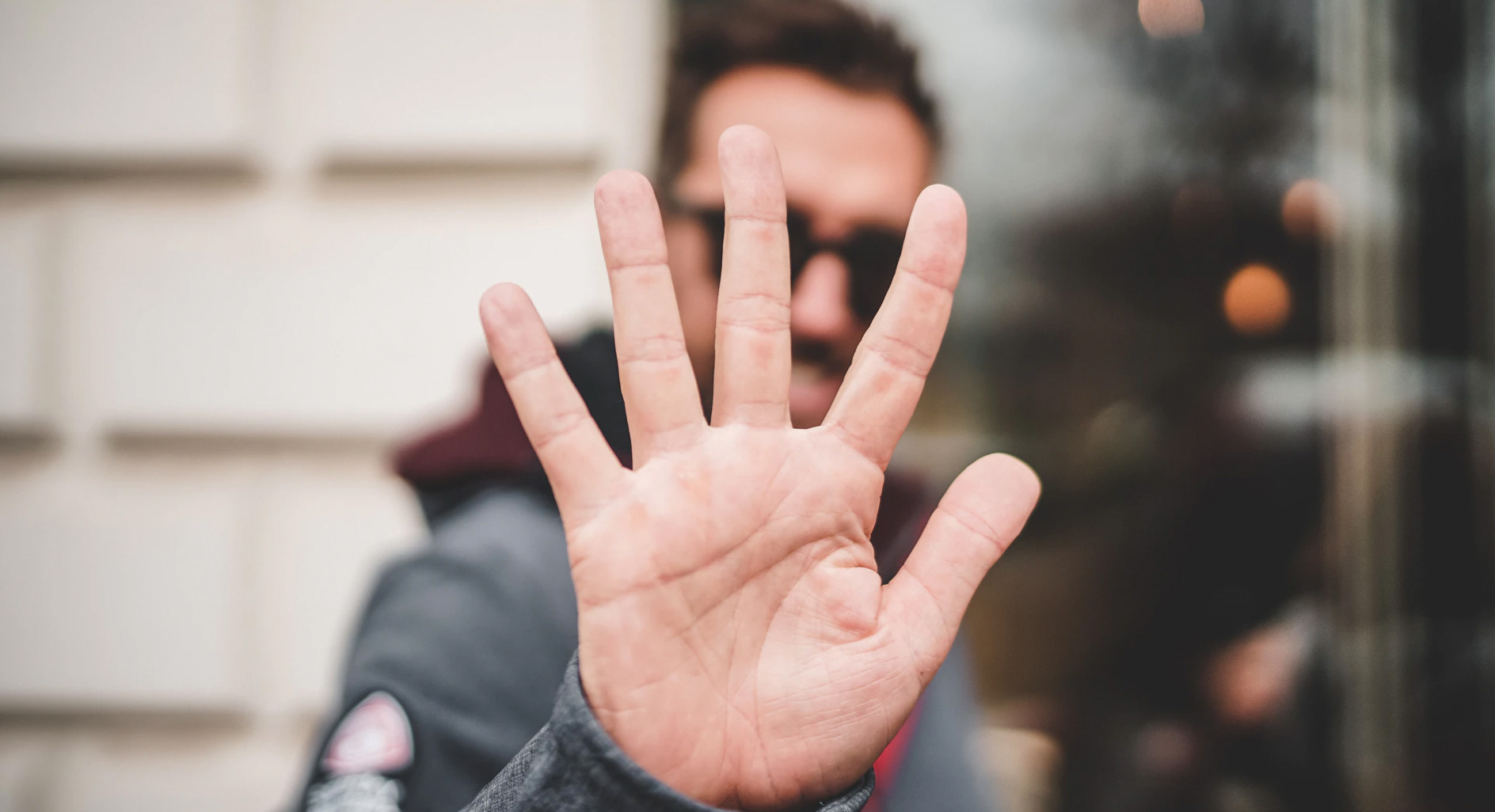 Man holding up a hand to represent the number five. 