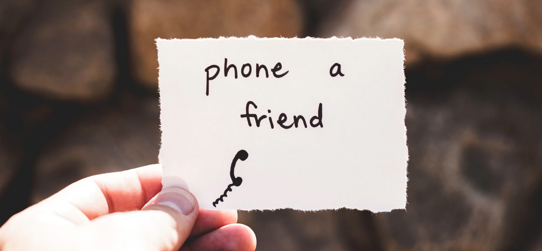 Person holding a piece of paper that says, phone a friend 