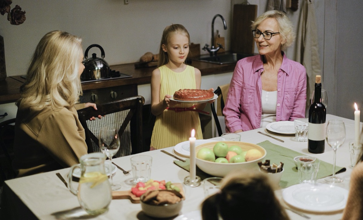 Family dinner with child serving cake
