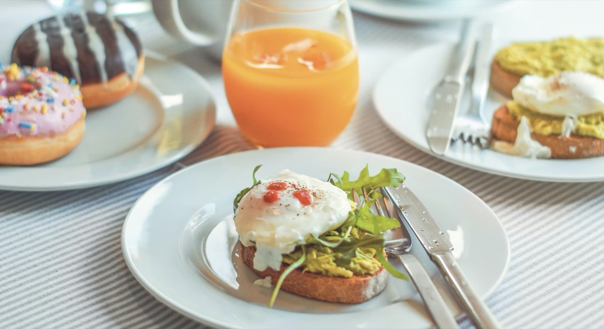 Avocado toast on a plate with donuts on another plate for breakfast