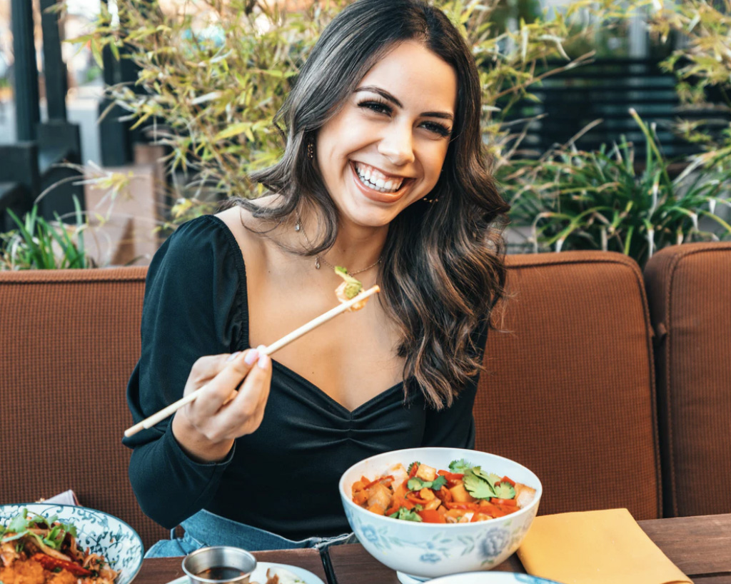 Girl eating meal with chopsticks. Unsplash - Nate Johnston