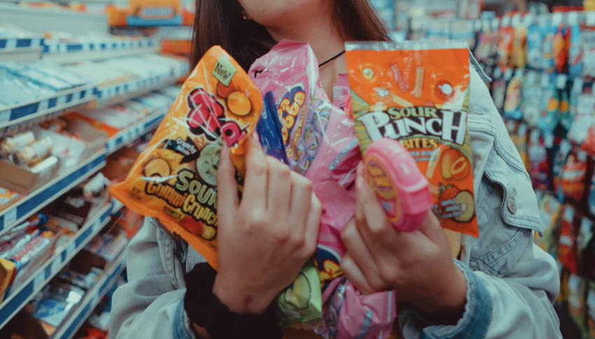 Girl in store picking up sugary sweets 