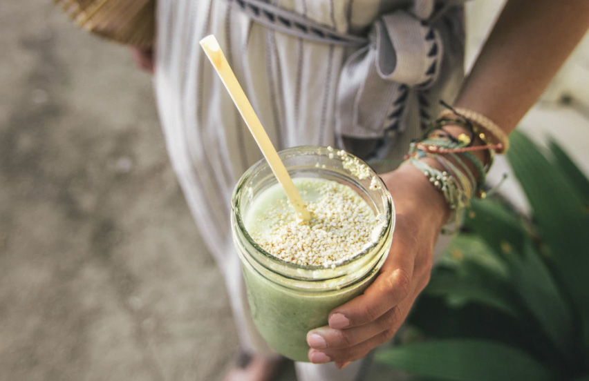 A woman holding a green smoothie. 
