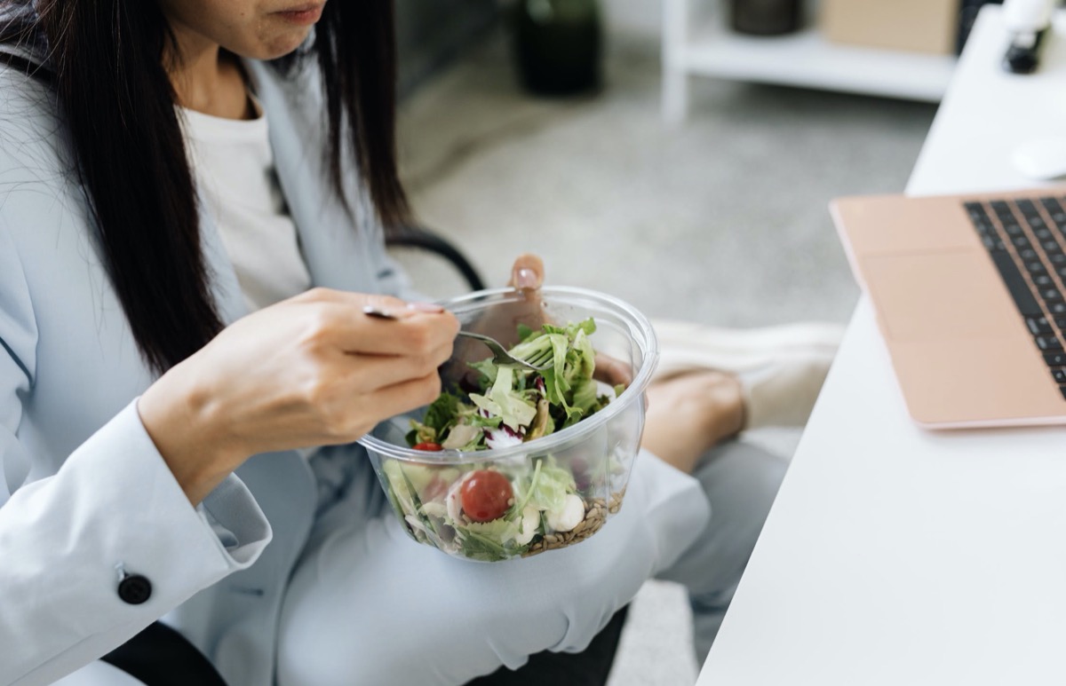 Woman eating salad while working 