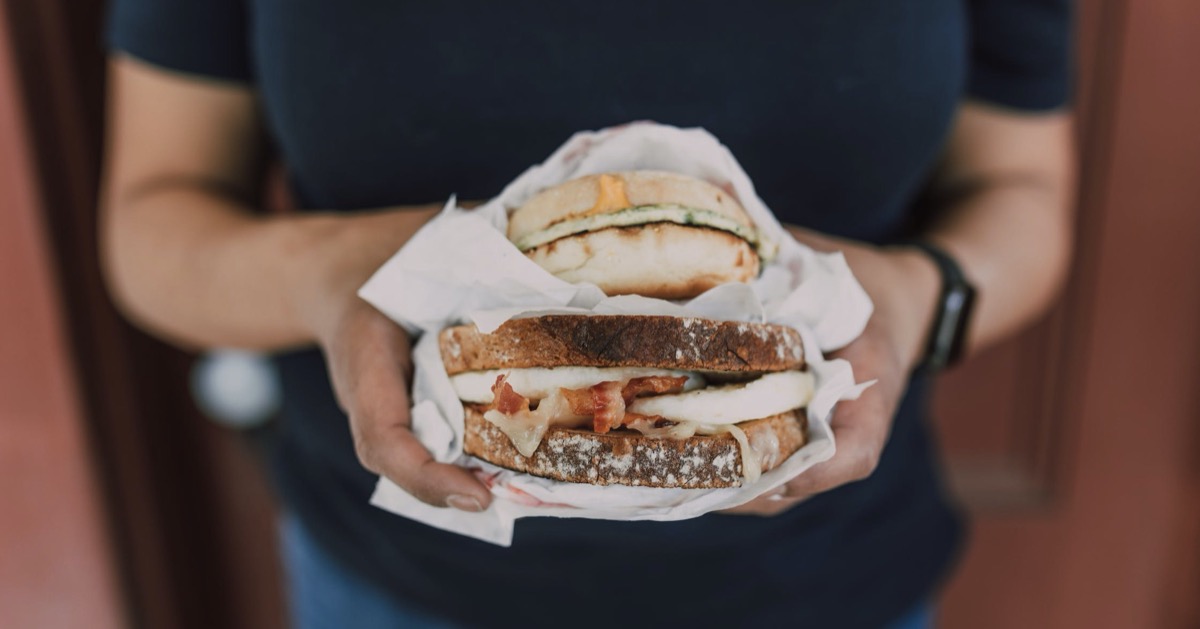 Woman holding sandwiches. Image: Pexels - RODNAE Productions