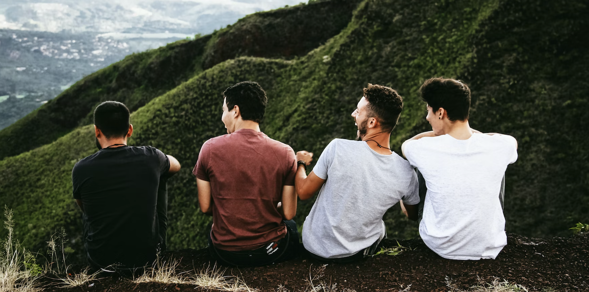 Men sitting together on top of mountain. Image: Unsplash - Matheus Ferrero