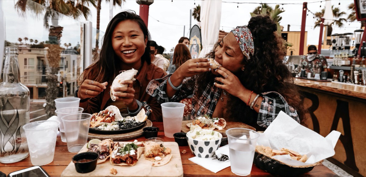 Two girls enjoying a meal out while traveling Unsplash - kevin turcios