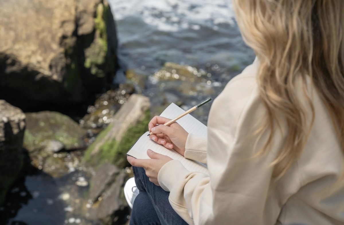 Woman sitting on rocks and journaling. Image: Pexels - Kevin Malik
