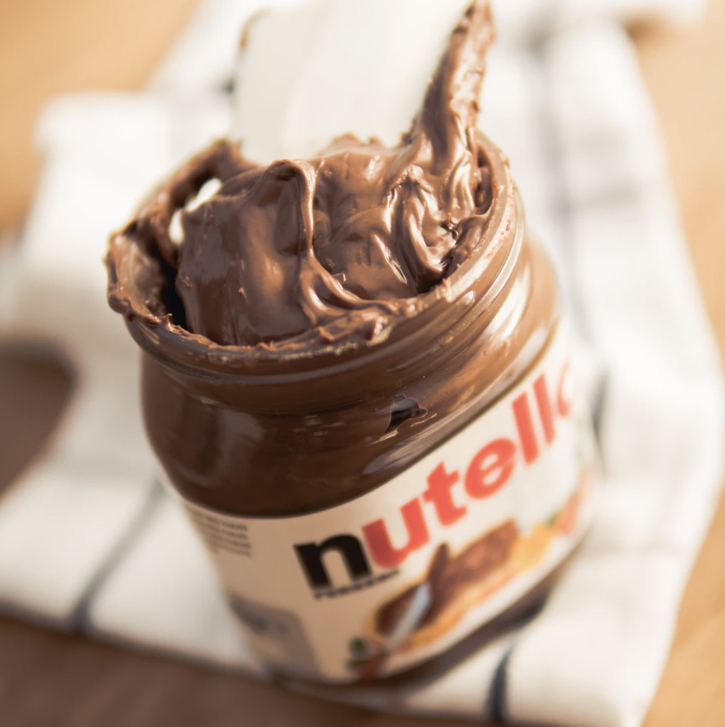 A jar of nutella with a spoon inside of it 