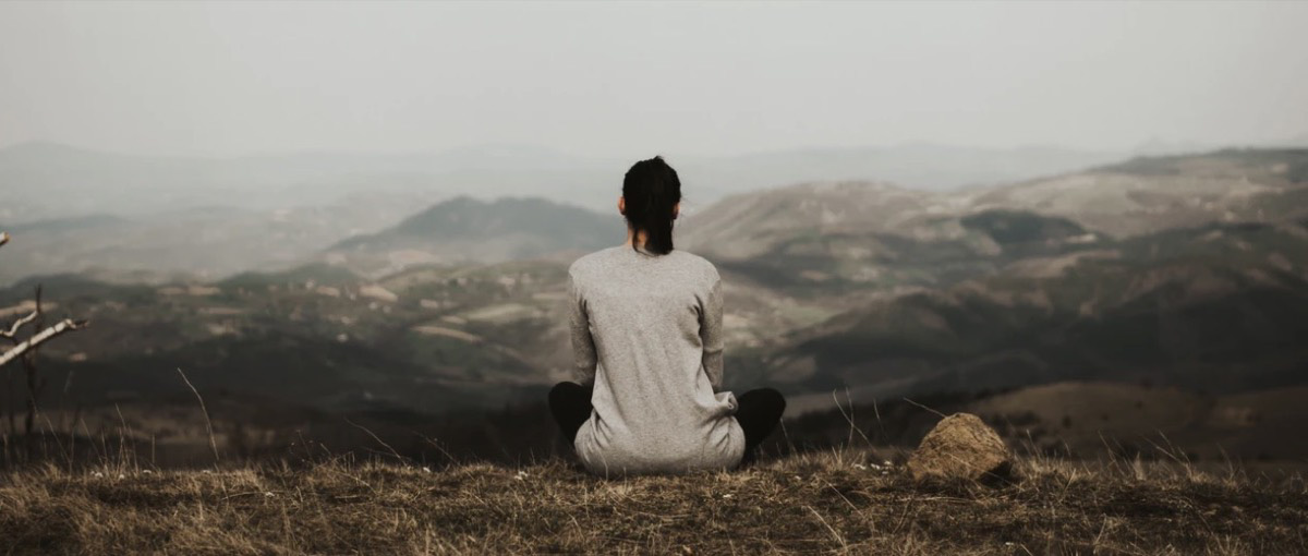 Woman sitting outside meditating.