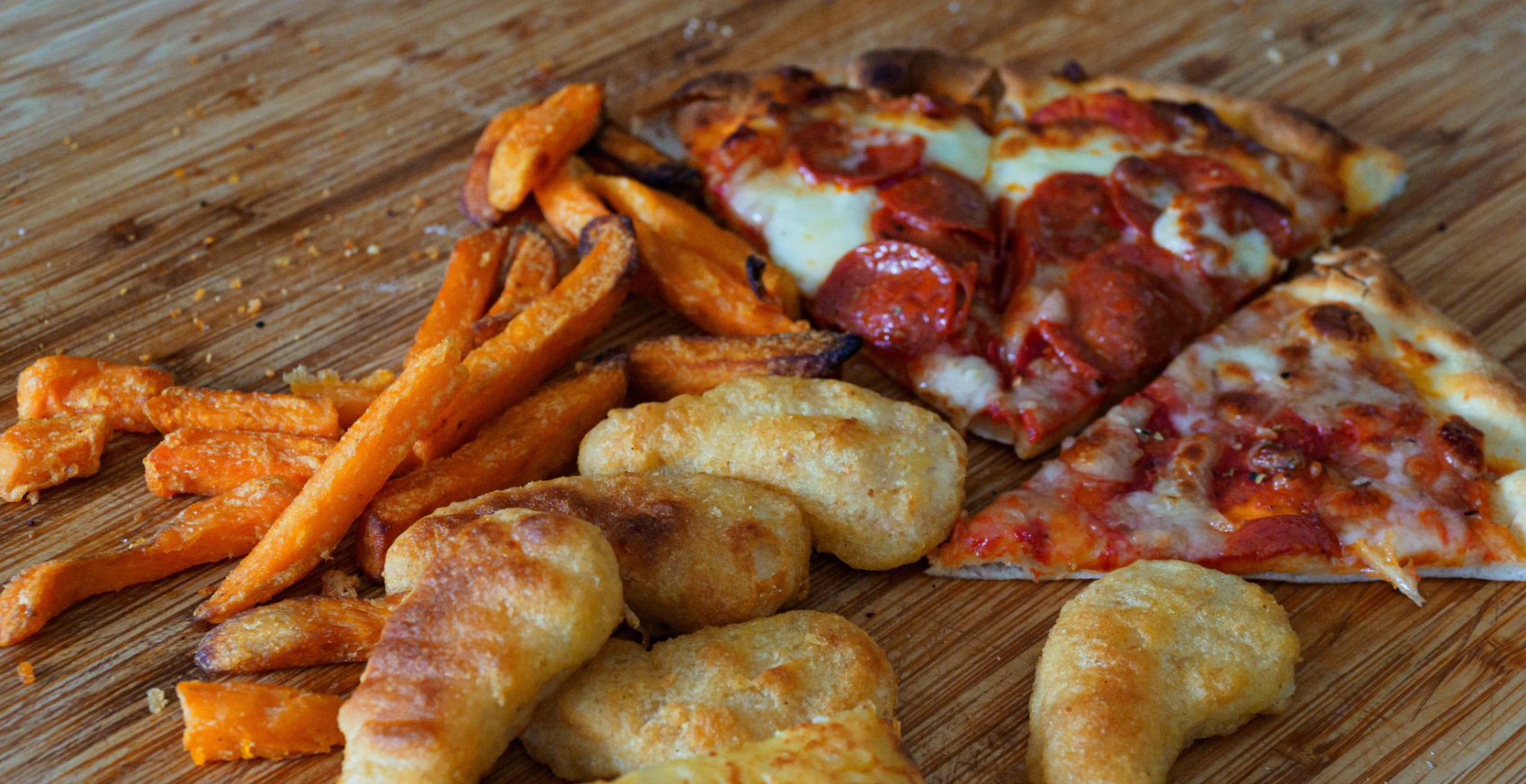 Plate with pizza french fries and chicken fingers.