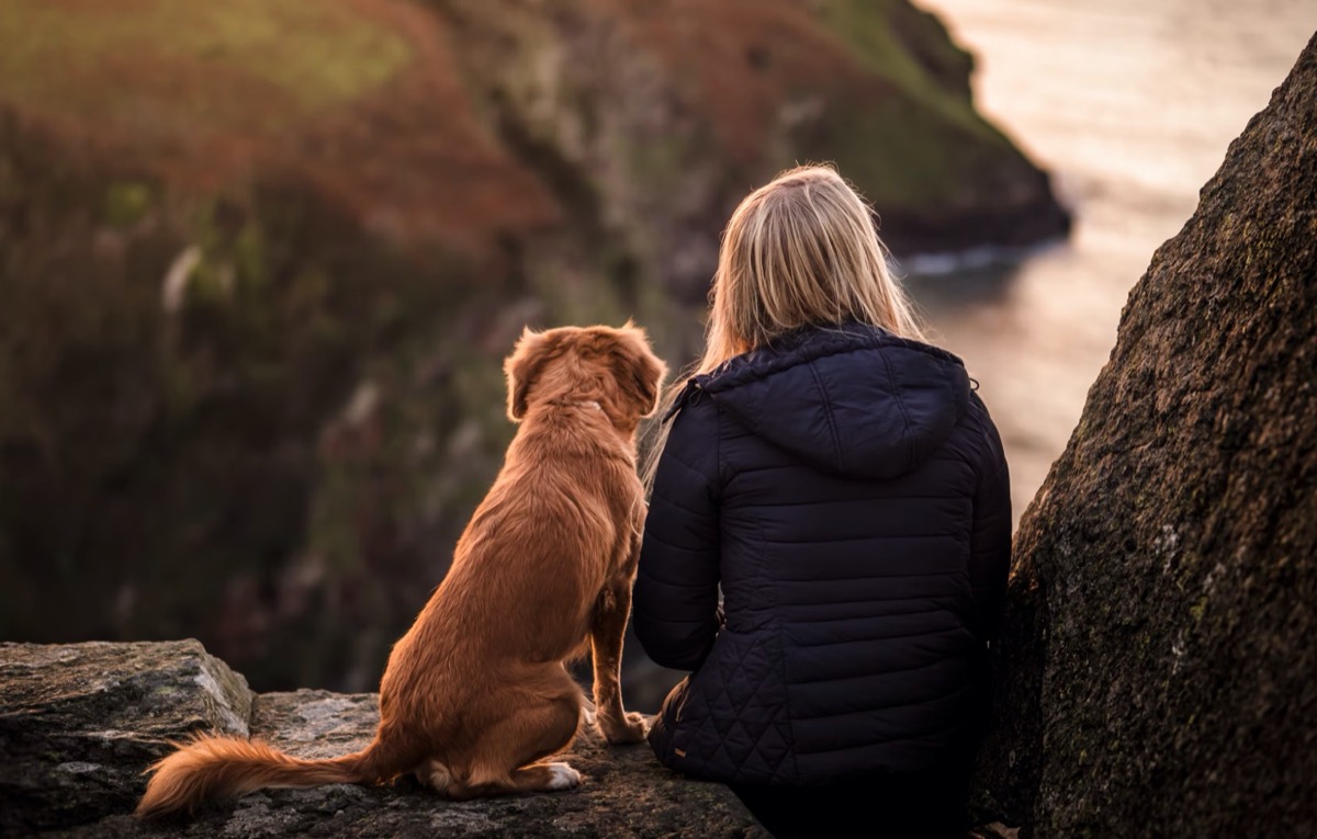 Woman sitting with dog on rocks