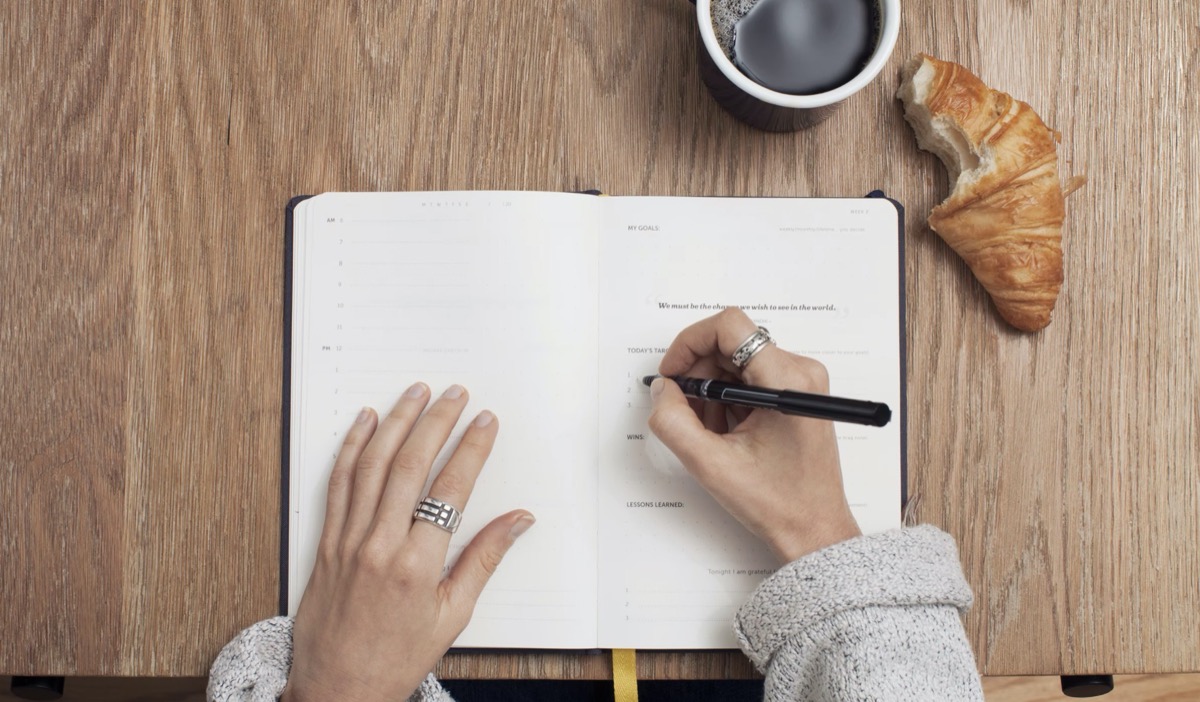 Woman writing in journal with goals 