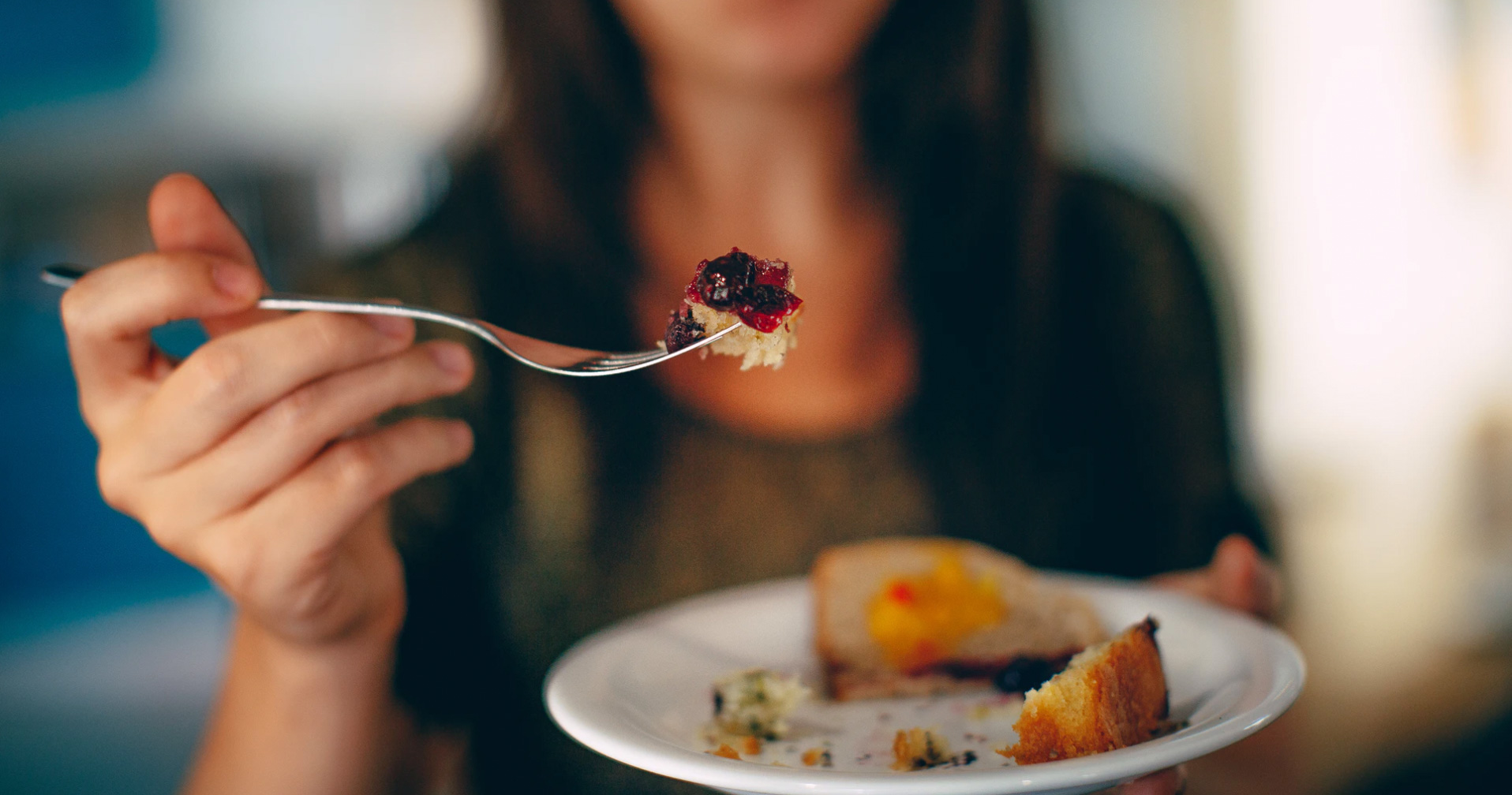 Woman with fork in her hand with food. Unsplash: Helena Lopes