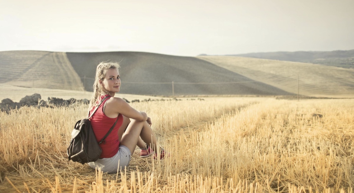 Woman looking back while sitting outside in a field