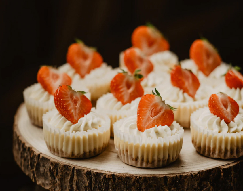 Mini cheesecakes with strawberries being served.