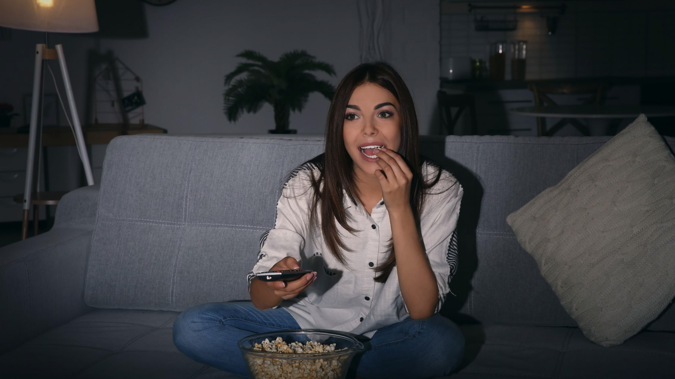 woman eating popcorn while watching TV