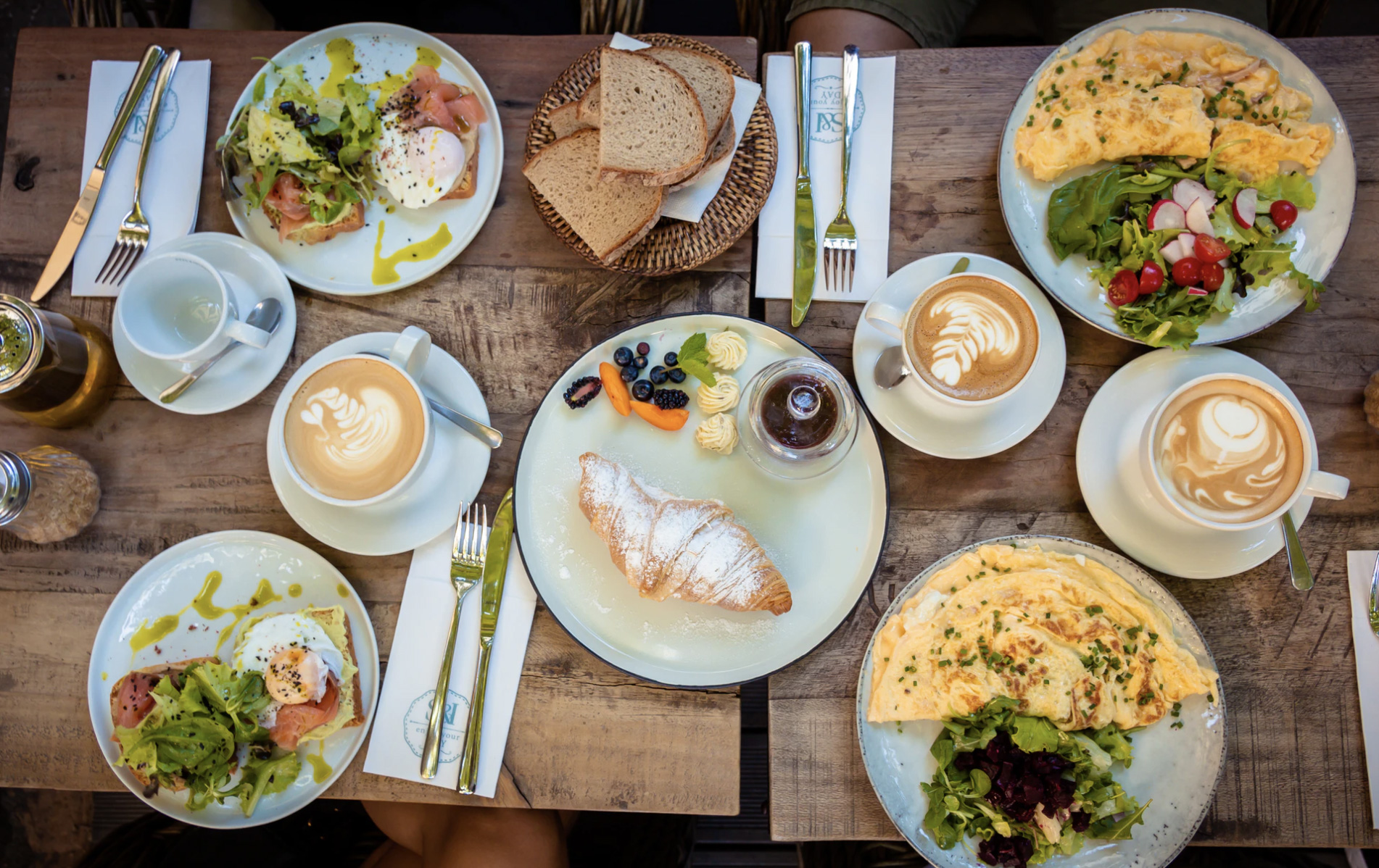 A large table with breakfast foods of eggs coffee and croissants