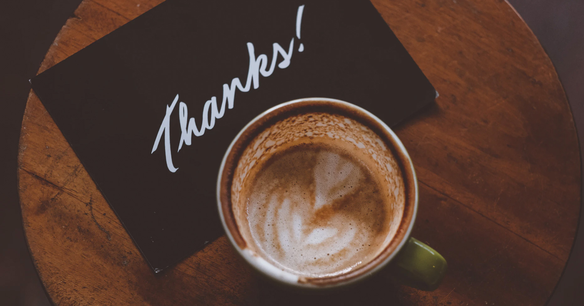 A table with a coffee mug and thank you card. 