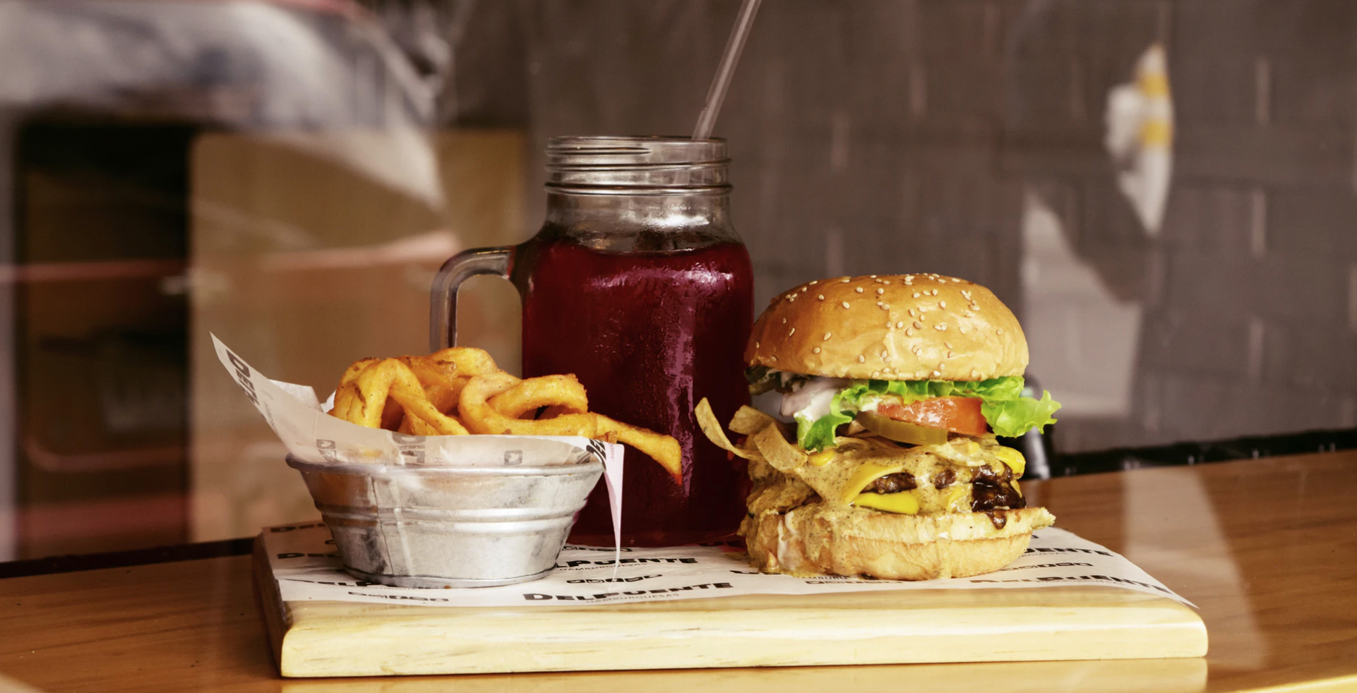 A plate with a smoothie, hamburger, and french fries.