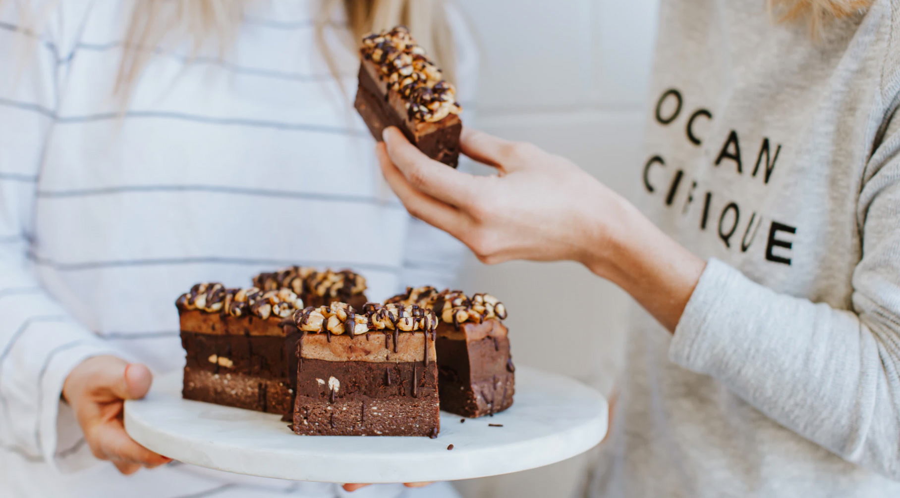 Two girls holding a tray of cake. 